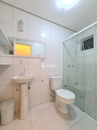 Foto de um banheiro interno com azulejos brancos e louças sanitárias.