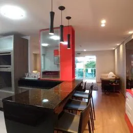 Vista de uma área de cozinha com bancada escura e armários vermelhos.