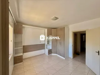 Sala de estar com armários de madeira e piso de cerâmica clara.