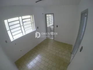 Hall com piso de cerâmica claro e janela com venezianas.
