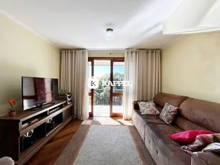 Sala de estar com sofá marrom e televisão em ambiente claro.
