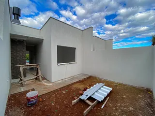 Fachada externa de uma residência em construção com área de terra no primeiro plano.