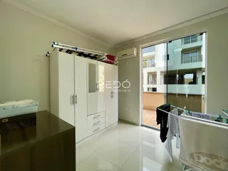 Interior de um cômodo com armários brancos e porta de vidro.