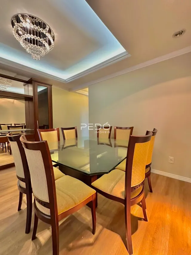 Sala de jantar com mesa de vidro e cadeiras de madeira em um ambiente claro.