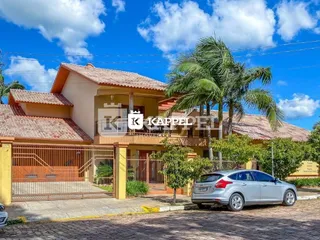 Fachada de uma residência em Lajeado, Brasil, com telhado de telhas e vegetação.