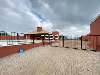 Pátio externo com piso de tijolos e cerca de metal em uma propriedade em Lajeado.