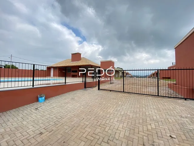 Pátio externo com piso de tijolos e cerca de metal em uma propriedade em Lajeado.