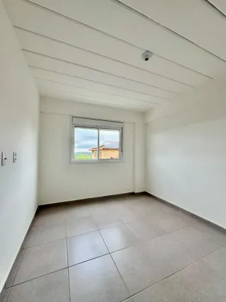 Foto de um cômodo interno com piso de cerâmica e teto de vigas brancas.