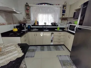 Foto de uma cozinha com armários brancos e bancadas escuras.