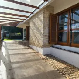 Vista de uma área externa com piso de cerâmica e estrutura de madeira.