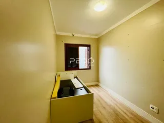Vista de um corredor interno com paredes amarelas e piso de madeira.