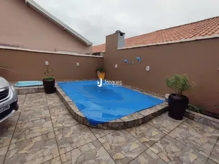 Foto da área externa com piscina e piso de cerâmica.