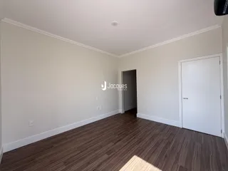 Foto de um ambiente interno com piso de madeira e paredes brancas.