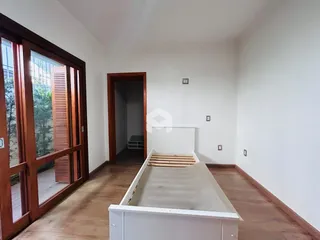Quarto com piso de madeira e porta de vidro na sala.