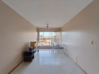 Ambiente interno de uma sala de estar com piso de cerâmica e vista para o exterior.