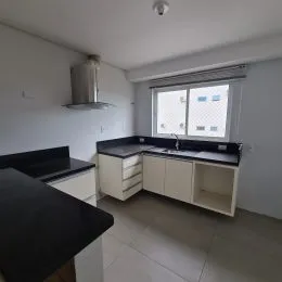 Foto interna de uma cozinha com armários e bancadas escuras.