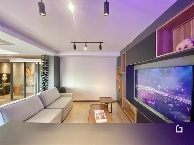Sala de estar moderna com sofá e parede de TV.