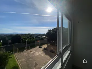 Vista de uma quadra esportiva e área verde vista pela janela.