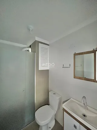 Foto de um banheiro com louças sanitárias brancas e bancada.