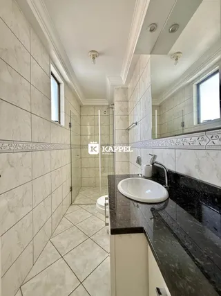 Banheiro com revestimento de azulejos brancos e bancada escura.
