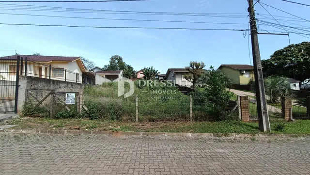 Vista da fachada de casas em Lajeado, Brasil, com cerca e vegetação.