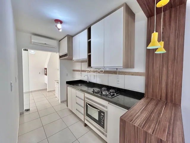 Foto de uma cozinha moderna com armários brancos e bancadas escuras.