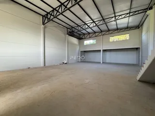 Espaço amplo com estrutura de telhado metálico e portas de garagem.