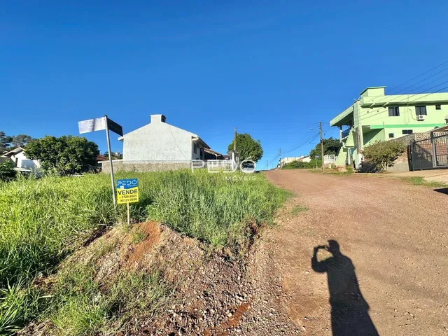 Vista externa de uma propriedade com terreno gramado e uma estrada de terra.