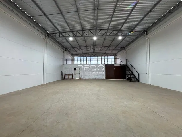 Espaço interno amplo com teto industrial e piso de concreto.