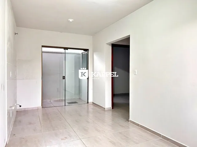 Um corredor interno com piso de porcelanato e acesso a um banheiro com box de vidro.