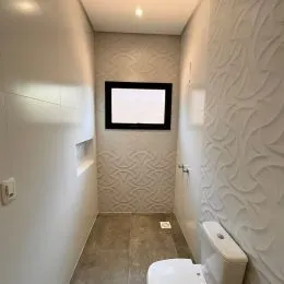 Corredor interno com paredes texturizadas de cor clara.