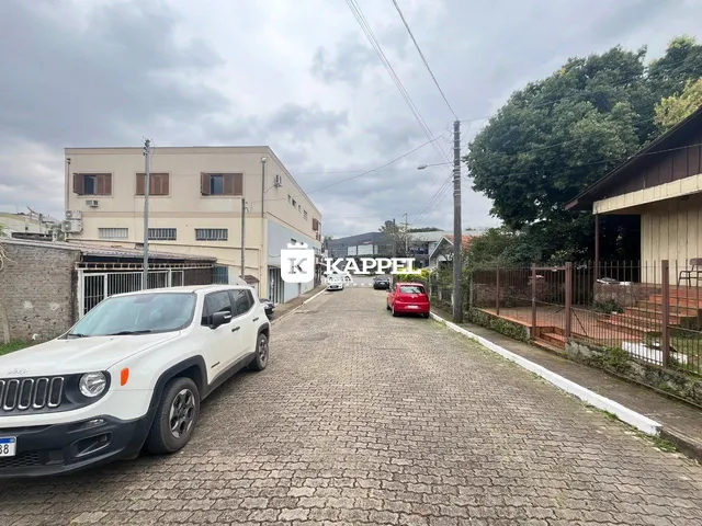 Vista externa de uma propriedade com um veículo estacionado em uma rua de paralelepípedos.