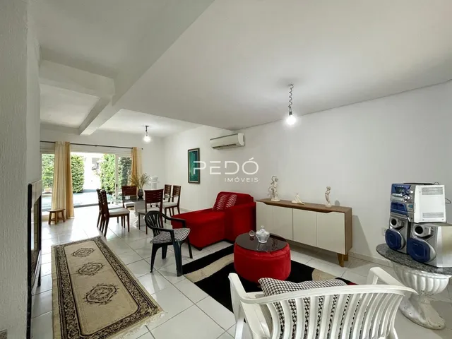 Sala de estar iluminada com piso de cerâmica e móveis de madeira clara.