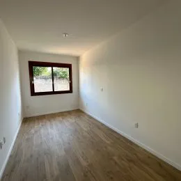 Uma foto interna de um cômodo com piso de madeira e janela.