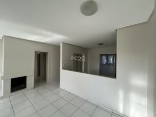 Ambiente interno de uma sala com piso de cerâmica branca e lareira.