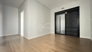 Ambiente interno com piso de madeira clara e porta de vidro na sala.