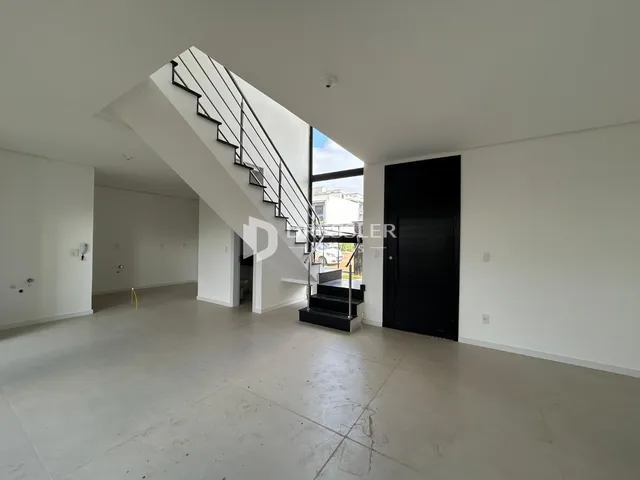 Vista de um corredor com escadaria em um imóvel moderno.