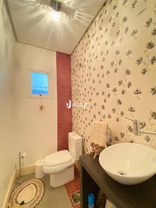 Banheiro interno com revestimento de parede e louças sanitárias.