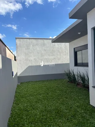 Vista externa de uma casa moderna com jardim verde.