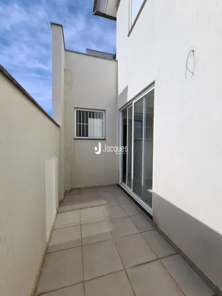 Corredor interno com paredes brancas e piso de cerâmica.
