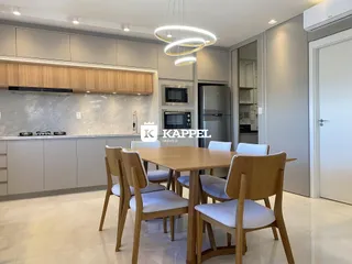 Foto de uma sala de jantar com mesa de madeira e armários na cozinha.