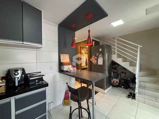 Vista da cozinha moderna com ilha e escada em apartamento em Lajeado.