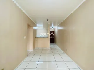 Corredor interno de uma residência com piso de cerâmica branca.