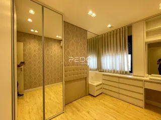 Quarto com paredes decoradas em papel de parede e piso de madeira clara.