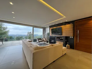 Sala de estar com sofá bege e grande janela com vista panorâmica.