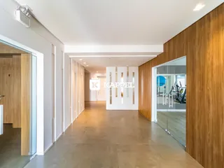 Corredor interno moderno com piso claro e revestimento de madeira.