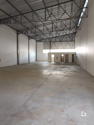 Espaço interno com estrutura de teto exposta e paredes brancas.