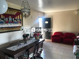 Sala de estar com mesa de madeira e assentos vermelhos.