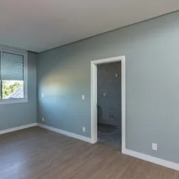 Foto de uma sala com piso de madeira clara e paredes cinza.