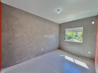 Interior de uma sala com paredes de concreto e piso de cerâmica.